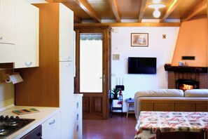 Une cuisine de taille réduite, équipée d’une cuisinière, de placards et d’un coin repas avec une table et des chaises.