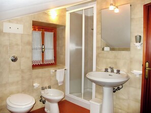 Une salle de bain avec deux toilettes, un bidet, un lavabo, une douche et un miroir.
