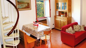 Un comedor con una mesa, sillas, un sofá rojo, un aparador de madera y una escalera.