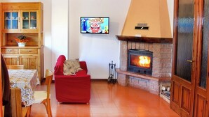 Una sala de estar con chimenea, televisor y comedor con armarios de madera y una mesa.