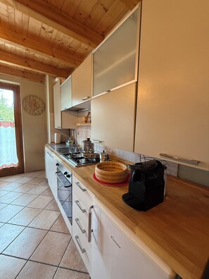Eine Küche mit Holzausziehtisch, einem Herd, Schränken und einer Uhr an der Wand.
