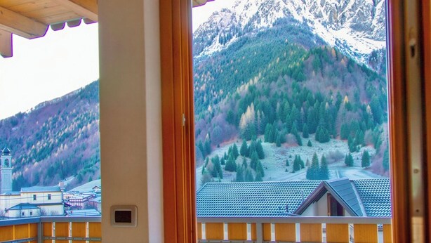 A room with a view of a mountain landscape, a wooden ceiling, and a window with a wooden frame. - Quater Pis - Casa in Scalve (Colere)