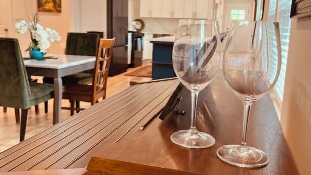 Een eethoek met een houten tafel, twee wijnglazen en een hanglamp.