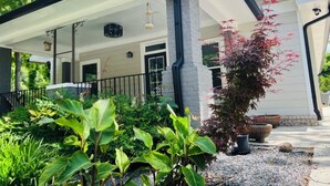 Een modern huis met een overdekte veranda, een stenen pilaar en een bloempot.