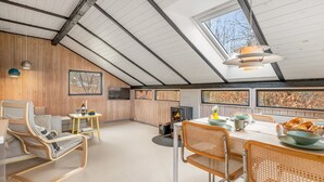 Un loft accogliente con soffitto alto, pareti in legno, zona pranzo con tavolo e sedie e un caminetto.