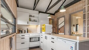 Una cucina moderna con mobili bianchi, forno integrato, piano cottura e una grande isola con lavello.