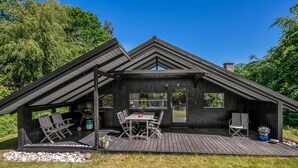 Un'accogliente baita moderna in legno con veranda, zona pranzo e ampia finestra.