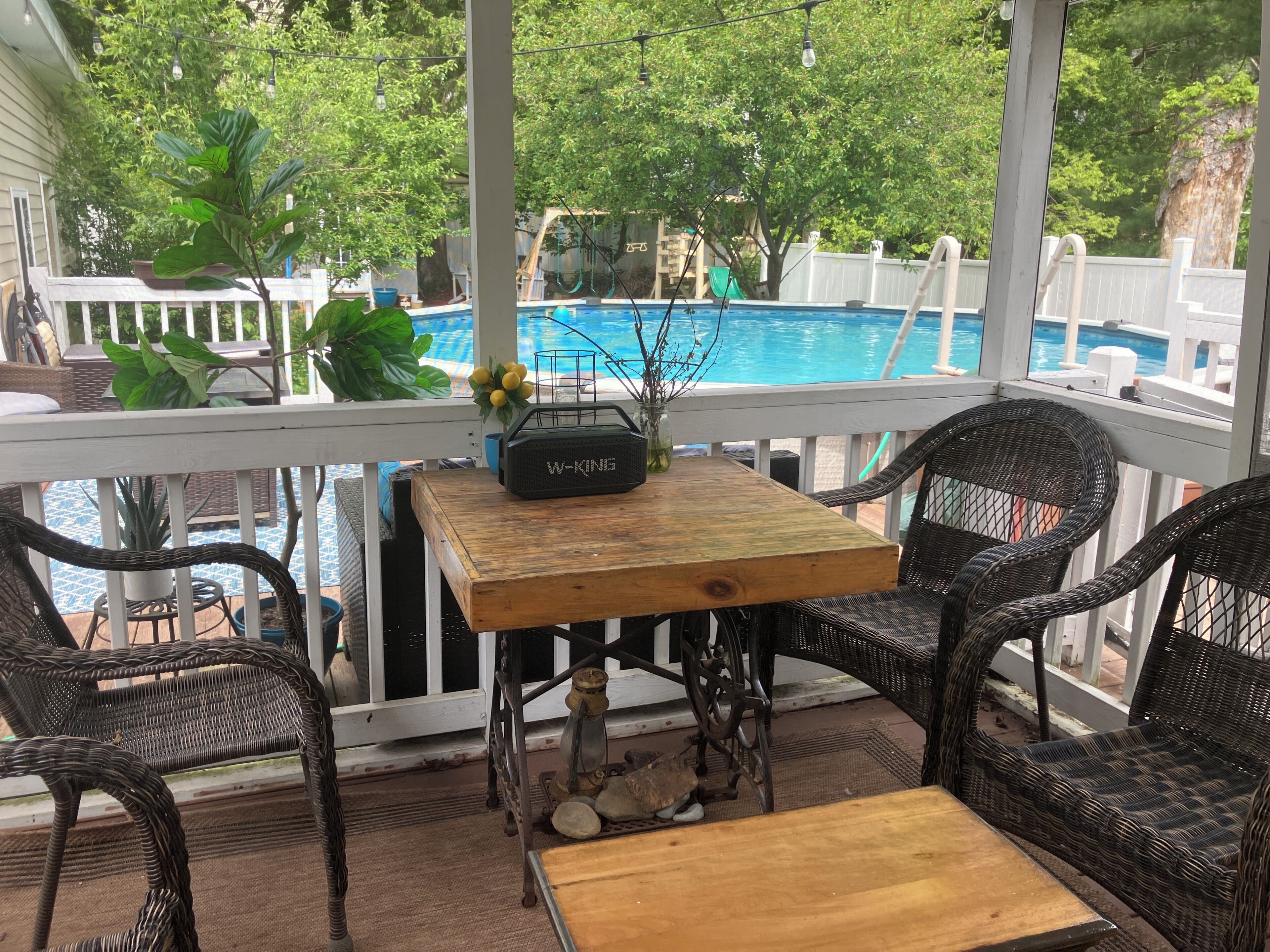 Un espace extérieur abrité, aménagé avec des meubles en osier, une table en bois et une piscine en arrière-plan.