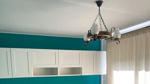 A bedroom with a bed, built-in storage, a hanging light fixture, and a window with curtains.