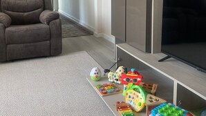 A living room with a sofa, TV, cabinets, and children's toys.