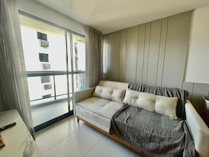 Ein modernes Wohnzimmer mit Sofa, Balkon und Blick auf Gebäude.