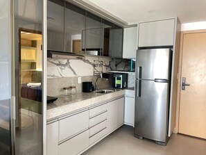 Eine moderne Küche mit Edelstahl-Kühlschrank, Marmorarbeitsplatte und Glastüren an den Schränken.