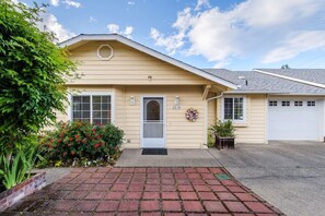 A single-story house with a beige exterior, a front door, a garage, and a brick driveway.