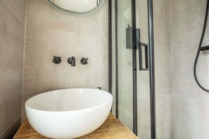 Une salle de bain moderne avec un grand lavabo sur pied blanc, une douche en verre et un design minimaliste.