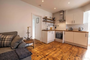A compact kitchen with white cabinets, a wooden countertop, and a built-in oven.
