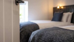 A hotel room with a bed, a headboard, and a door with a handle. - Ty Llwyd Ceibwr - Modern apartment (Saint Dogmaels)