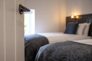 Une chambre d’hôtel avec un lit, une tête de lit et une porte dotée d’une poignée.