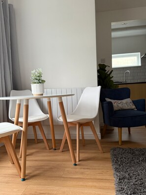 Una sala moderna con una mesa de comedor, sillas, un sofá azul y una cocina al fondo.