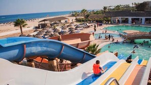 Parque acuático con una gran piscina, toboganes y vistas a la playa.