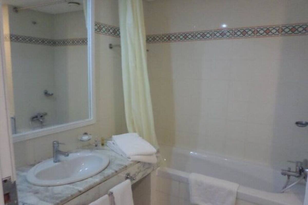 Un baño con lavamanos, espejo y bañera.