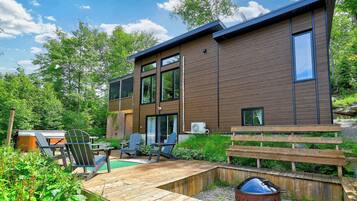 Une maison moderne à deux étages dotée d’une terrasse, d’un espace salon extérieur et d’un coin barbecue.