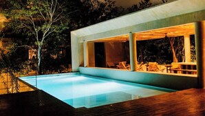 Ein modernes Haus mit Swimmingpool, großen Fenstern und Gartenmöbeln.