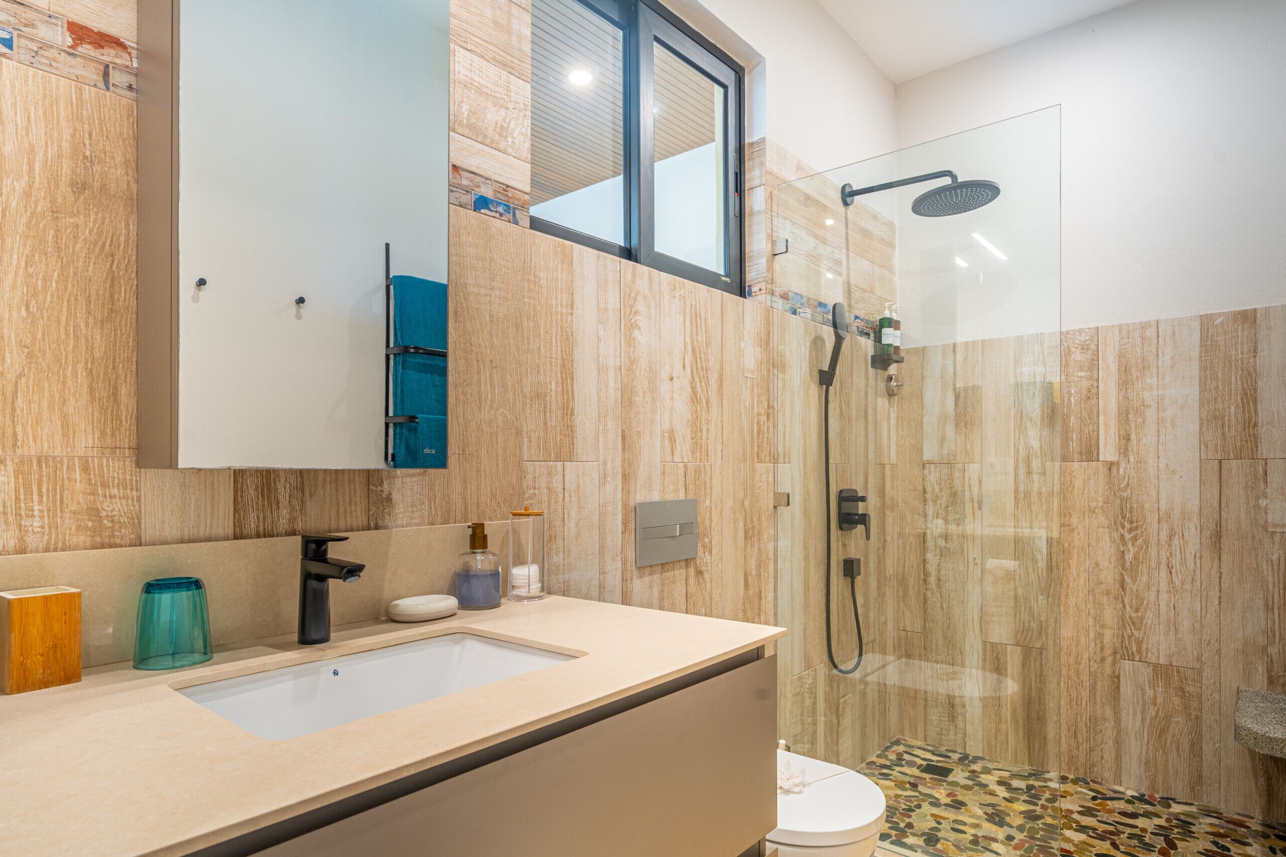 A modern bathroom with a glass shower enclosure, a sink with a mirror, and a toilet.