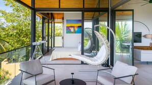 A modern interior with a glass balustrade, a hanging chair, and a dining area. - Stealing Time Costa Rica (Parrita)