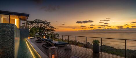 Eine moderne Außenterrasse mit Pool, Lounge-Bereich und Meerblick.