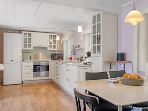 A modern kitchen with white cabinets, a wooden countertop, and a dining area with a table and chairs. - "Aslag" - 3.5km from the sea by Interhome (Læsø)