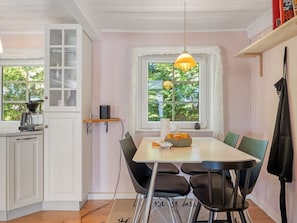 A kitchen with a dining table, chairs, a coffee machine, a window with a view, and a hanging light fixture. - "Aslag" - 3.5km from the sea by Interhome (Læsø)