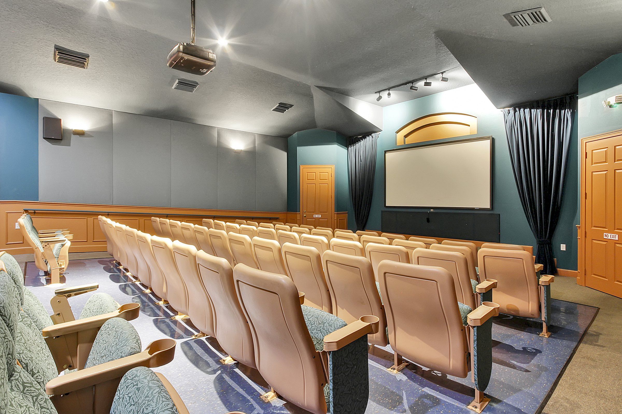 A theater with rows of seats, a screen, and a projection booth.