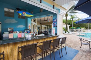 Eine Bar mit Blick auf den Pool, inklusive einer Theke mit verschiedenen Artikeln und Liegestühlen.