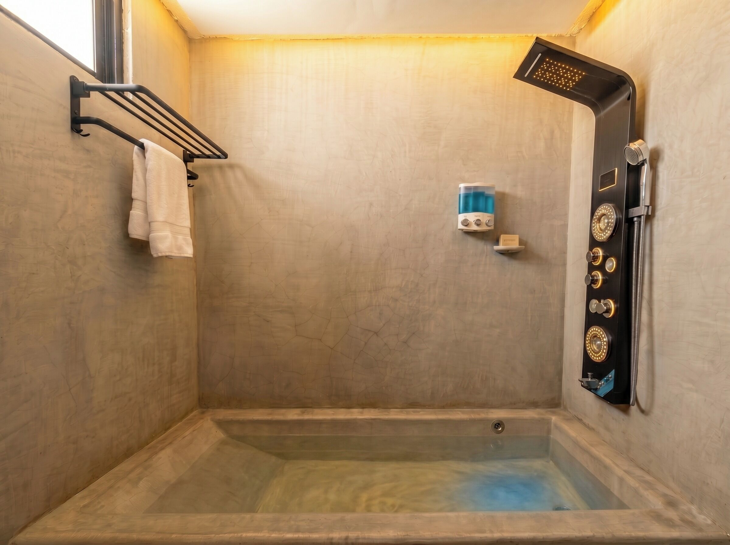 Ein kleiner, quadratischer Duschbereich mit integrierter Badewanne, einem Handtuchhalter und einer Handbrause.