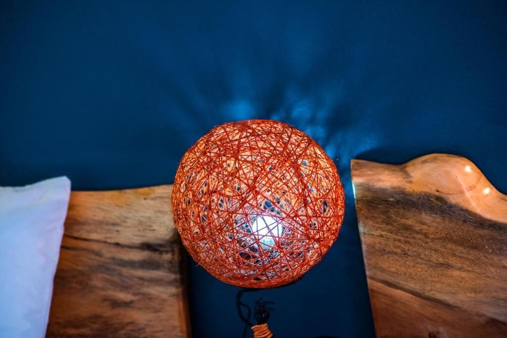 Un luminaire sphérique, rouge et tressé, posé sur une surface en bois.