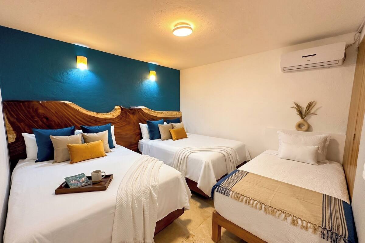 A hotel room with two beds, a wooden headboard, a ceiling light, and an air conditioning unit.