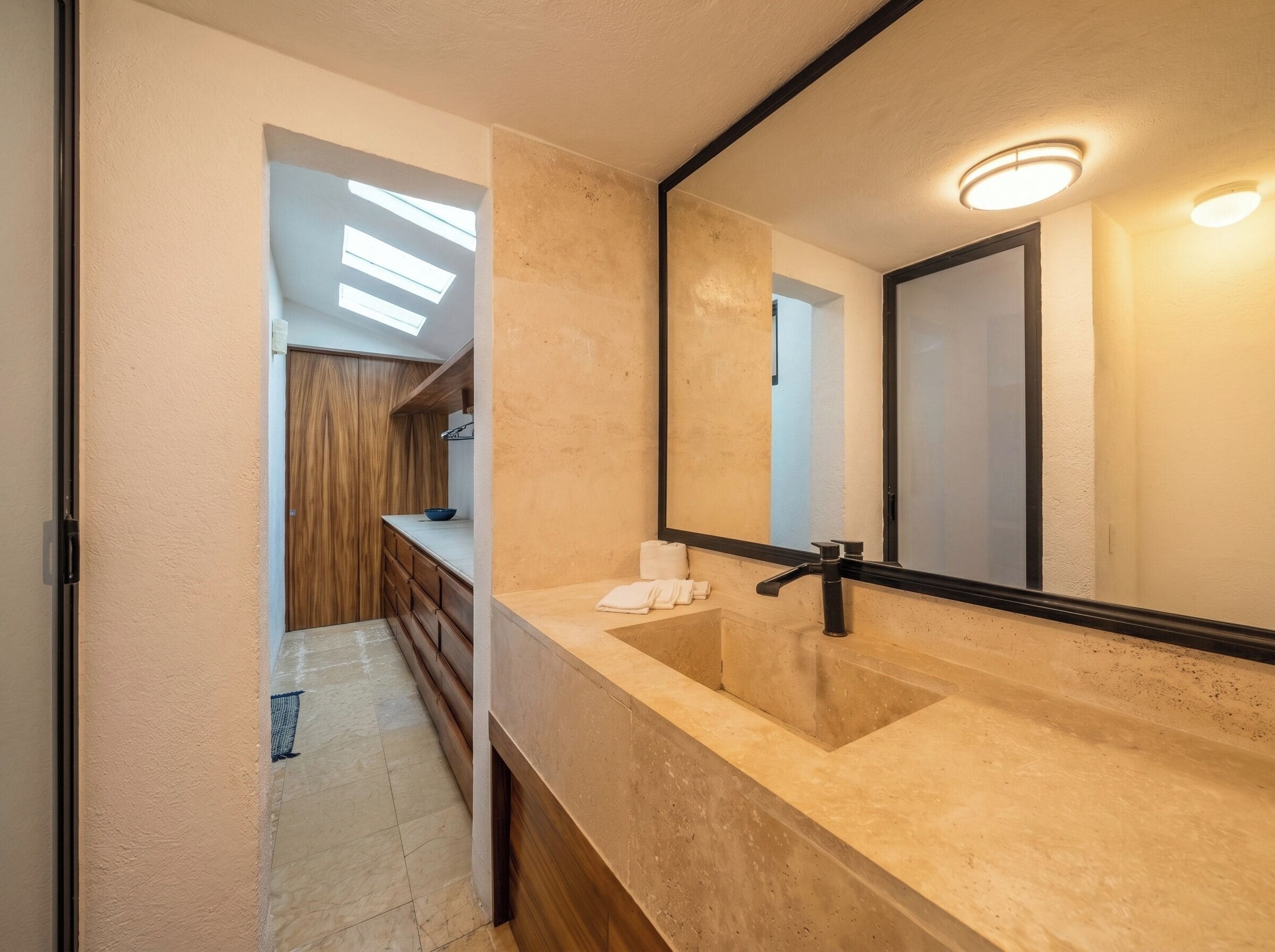 Un baño con un espejo grande, un lavamanos y una zona de ducha.