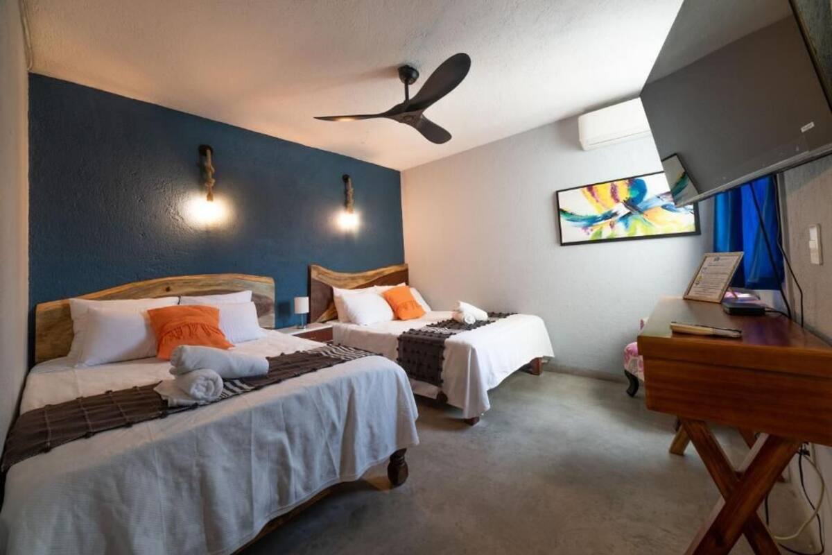 A hotel room with two beds, a ceiling fan, a TV, and a desk.