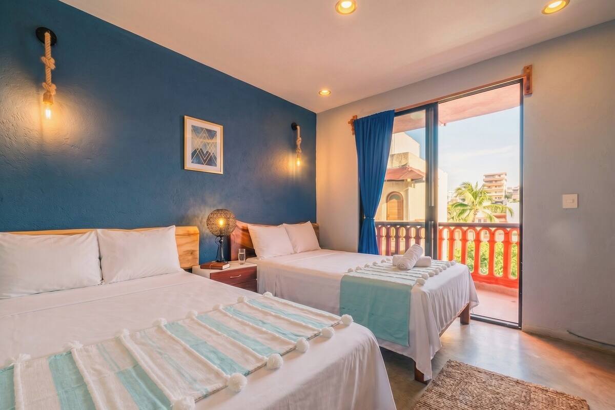 A hotel room with two beds, a balcony with a view, and a decorative wall light.