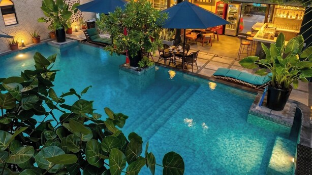 A rooftop pool with lounge chairs and umbrellas, surrounded by greenery and a bar area. - Zihua Mia Hotel Boutique  (Zihuatanejo)