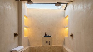 A modern bathroom with a freestanding bathtub, a small sink, and two wall-mounted lights. - Zihua Mia Hotel Boutique  (Zihuatanejo)
