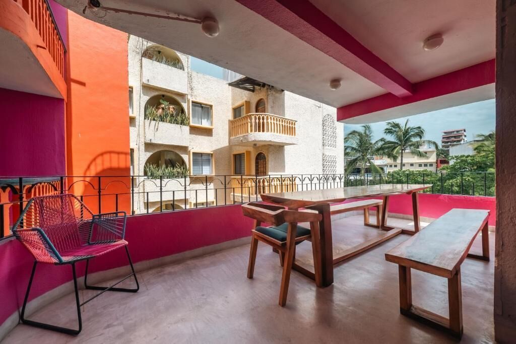 A balcony with a table, chairs, and a view of a building with balconies.