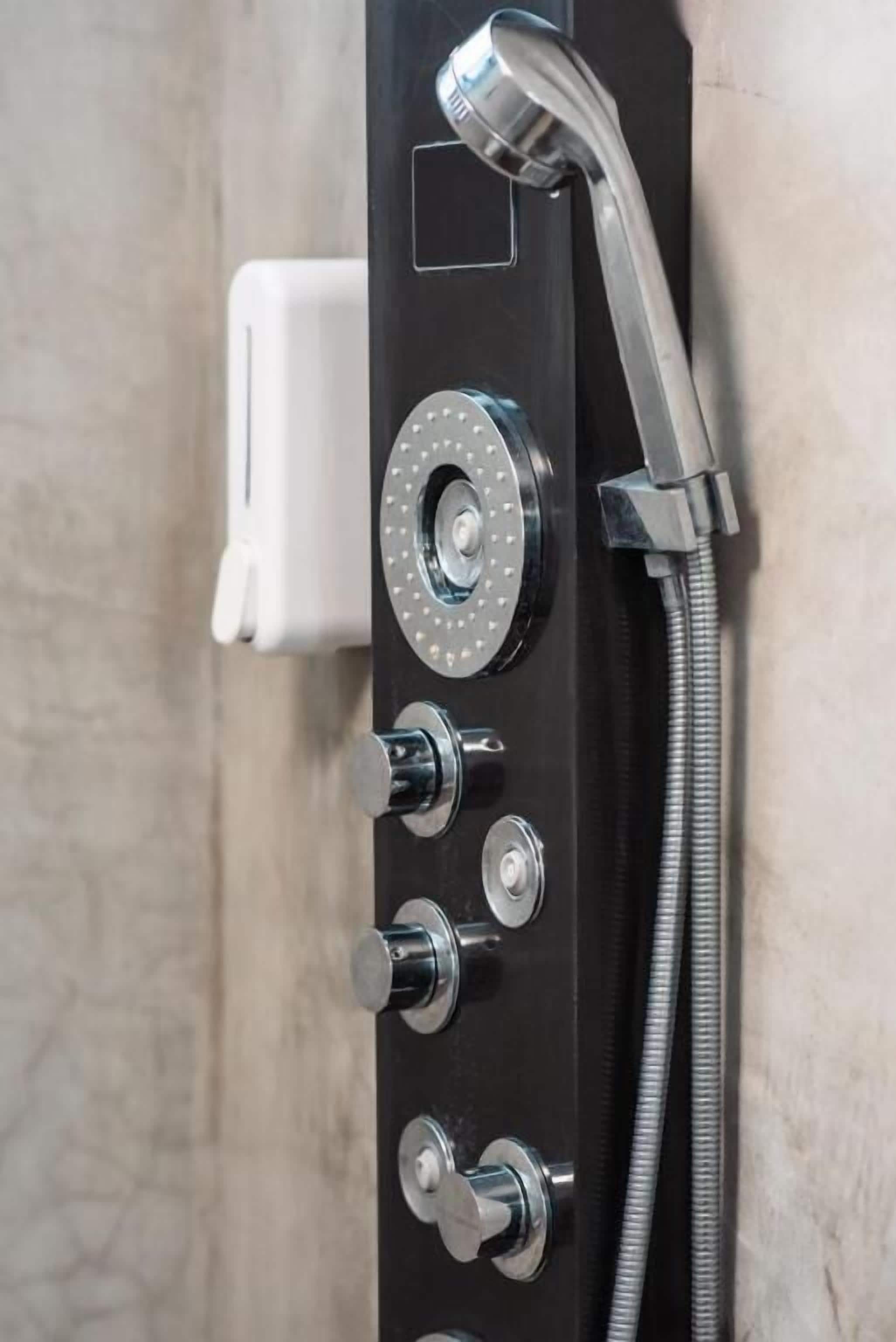 A shower control panel with multiple knobs and a handheld showerhead.