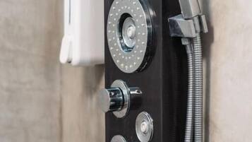 Un panel de control de ducha con varias perillas y un cabezal de ducha manual.