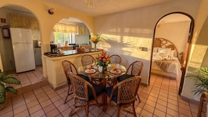 A compact hotel room with a dining area, kitchenette, and a bed with a headboard. - Zihua Mia Hotel Boutique  (Zihuatanejo)