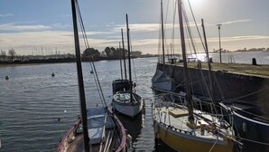A calm harbor with boats docked, a clear sky, and a distant city skyline.