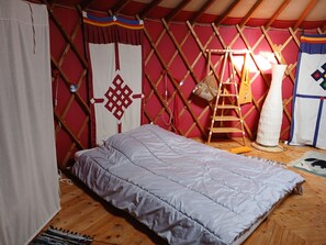Una habitación con cama, una escalera y una bolsa colgando.