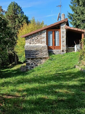 Una casa de piedra con puerta de madera, una antena parabólica y una pequeña escalera que lleva a la entrada.