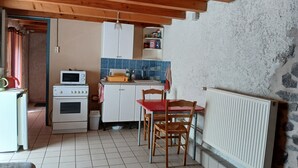 Eine kompakte Küche mit Mikrowelle, Herd und Schränken, einem Esstisch mit Stühlen und einer Steinwand.