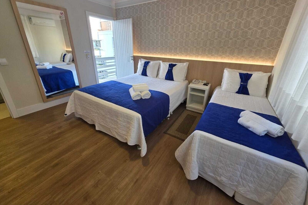 Une chambre d’hôtel avec deux lits, un miroir, une table de chevet et une vue sur l’extérieur.